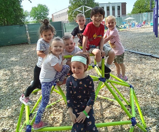 Young children gathered on a playground climber at Playful Minds Learning Center in Enfield, Connecticut.
