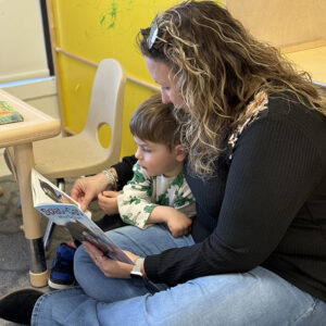 a woman reading a book to a toddler