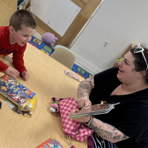 A woman showing a smiling child a page in a book