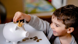 child putting coins in a piggy bank